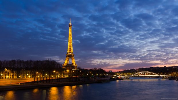 Eiffel tower at night behind Seine river