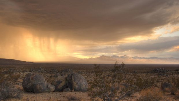 Rain clouds wallpaper moving across a desert.