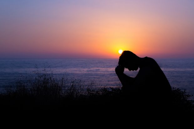 Man Praying by the Sea at Sunset