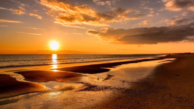 Sunset over rocky coastline with waves crashing, vibrant orange and blue sky, scenic Pacific Ocean landscape, evening seascape, tranquil beach scene, colorful sky, nature photography.