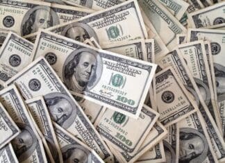 $100 US dollar bills in a pile, showcasing the design and serial numbers of the currency notes.