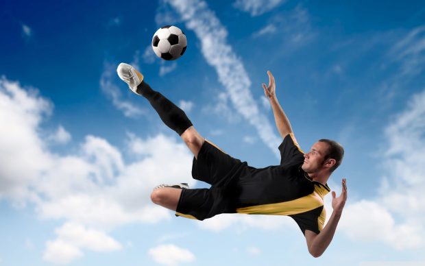 Football player kicking the ball in mid air wallpaper 2560x1600.