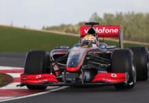 Formula 1 car on race track with Vodafone sponsorship, racing driver in helmet, Mercedes-Benz F1 team vehicle, high-speed motorsport, professional racing sports.