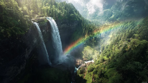Waterfall 4k wallpaper capturing multiple tiers of water dropping through lush valley with rainbow flare.