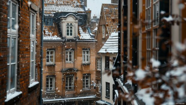 Snowfall covers old brick buildings and rooftops in a charming winter scene