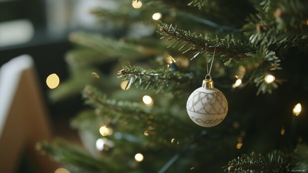 A Christmas ornament hanging on a fir tree branch with glowing Christmas lights in the background