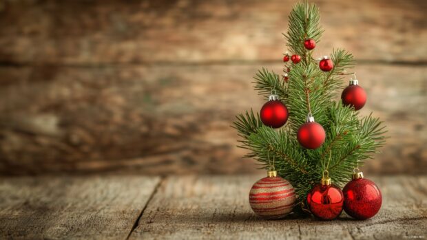 Small Christmas tree decorated with red ornaments on a wooden surface