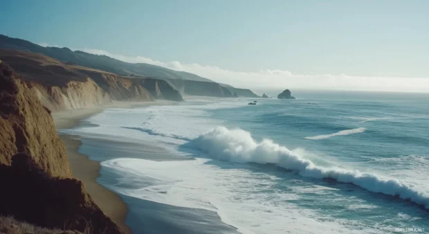A dramatic California beach with rugged cliffs and crashing waves.