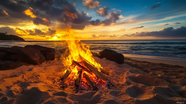 A beach bonfire burning brightly as the sun rises.