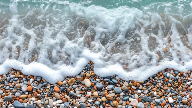 A beach with smooth, colorful pebbles and gentle waves lapping the shore.