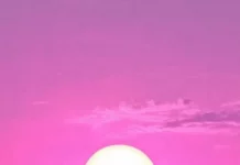 A bright pink purple sky on ocean, final sun rays vanish.