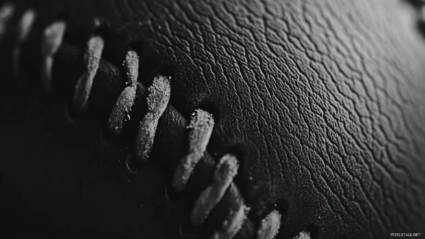 A close up of a baseball with rough leather in black and white.