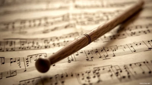 A conductors baton resting on large sheet music display.