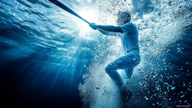 A dramatic underwater baseball player, swinging their bat as bubbles rise and light filters through deep blue waves.