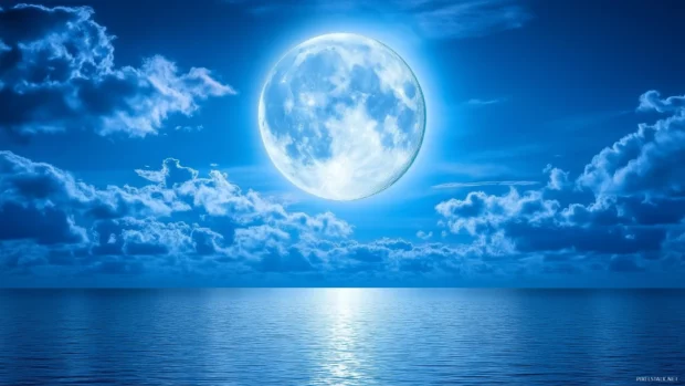 A full moon shines through wispy clouds, casting a soft glow over the calm ocean.