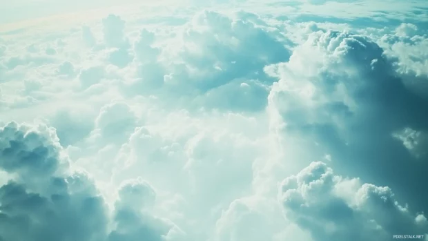 A high altitude sky viewed from an airplane window, with endless clouds and a soft gradient of blue to white.