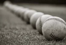 A line of baseballs on the grass in grayscale perspective.