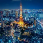 A lively Tokyo cityscape at night, with the Tokyo Tower and vibrant neon lights illuminating busy streets.