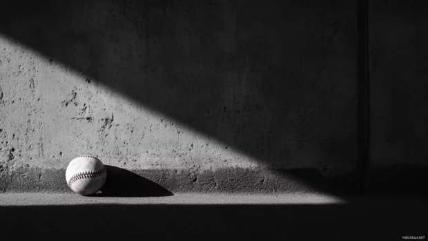 A lonely baseball in the dugout shadow.
