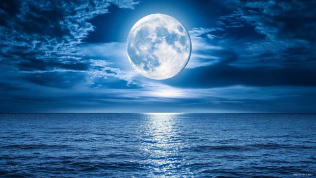 A luminous full moon shining through thin, wispy clouds, casting a soft glow over a calm ocean.