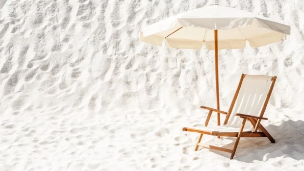 A minimalist design featuring a single beach chair and umbrella on a white sand background.