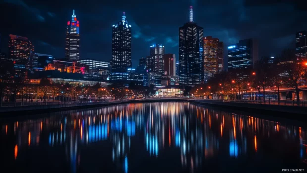A modern city skyline at night, filled with sparkling lights and reflections on a nearby river.