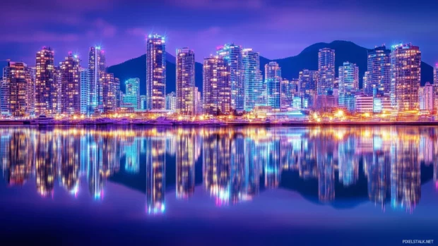 A night scene of a city waterfront with reflections of city lights dancing on the water.