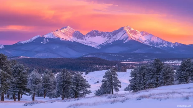 A radiant sky emerges beyond snow draped peaks.