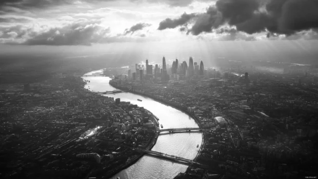 A river cuts across the monochrome city beneath drifting clouds.