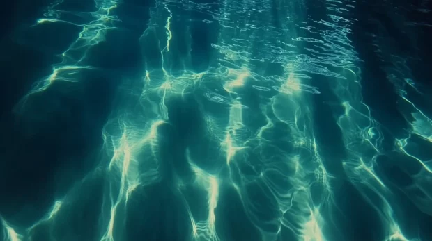 A serene underwater scene with sunlight piercing through the water surface, highlighting blue and turquoise gradients.