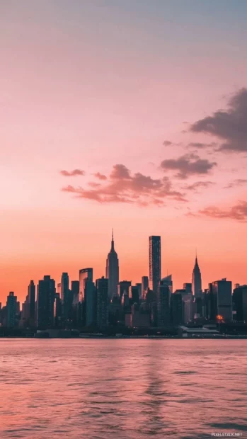 A soft pink and orange sunset framing the silhouette of New York skyline.