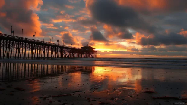A sunset beach with a pier extending into the ocean, the sky painted with rich, warm colors.