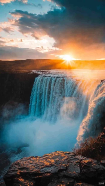 A waterfall shining with mist in the colors of sunrise.