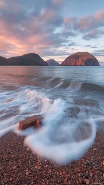 An aesthetic beach scene with soft waves and a sky of pastel pink and blue.