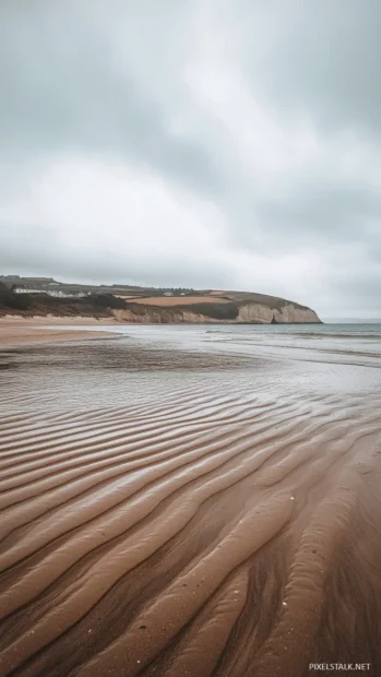 An aesthetic beach with gentle ripples in the sand and a calm, turquoise sea.