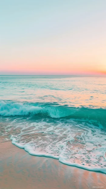 An early sunrise casts pastel hues over a calm, aesthetic beach.