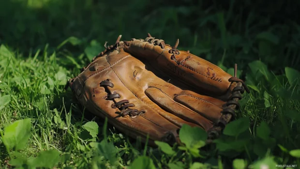 An old baseball glove resting on green grass field.