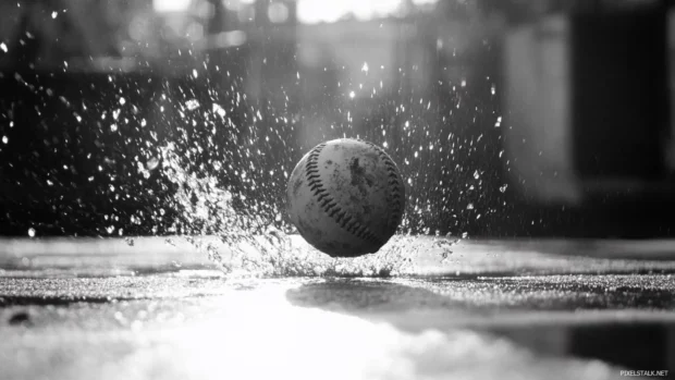 Backlit baseball bouncing on concrete in grayscale.