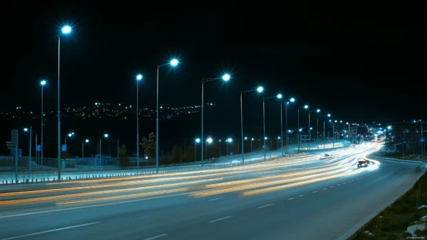 City bridge at night lit by streetlights and car trails.