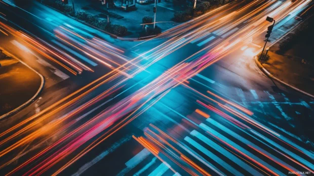 City intersection at night with long exposure capturing light trails from passing cars.