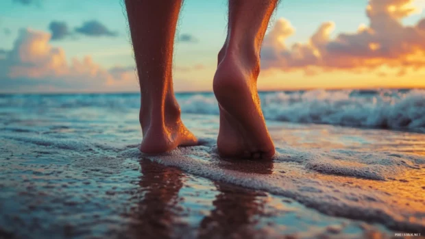 Close up of feet walking on sand at sunset with ocean and sky.