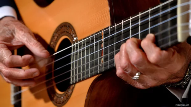 Close up of hands playing chords on acoustic guitar, HD music background image.