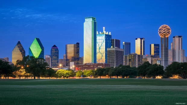 Close up view of Dallas landmarks like City Hall and the Sixth Floor Museum, illuminated at twilight.