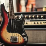 Electric bass guitar propped on vintage amp.