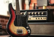 Electric bass guitar propped on vintage amp.