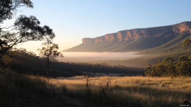 Gentle mist clings to the mountains as the sunrise begins.