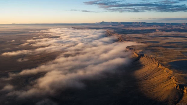 Glorious bands of cloud shimmer with morning colors across a vast sky.