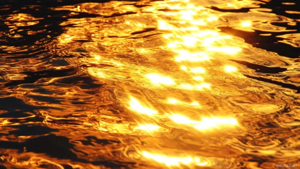 Golden reflections ripple across the surface of a lake at sunrise.