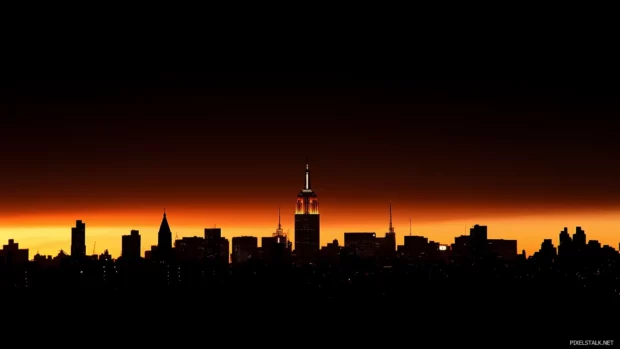 Iconic New York City skyline, sunset, Empire State Building, golden orange sky.