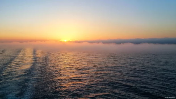 Mist curls over the water as a quiet sunrise begins.